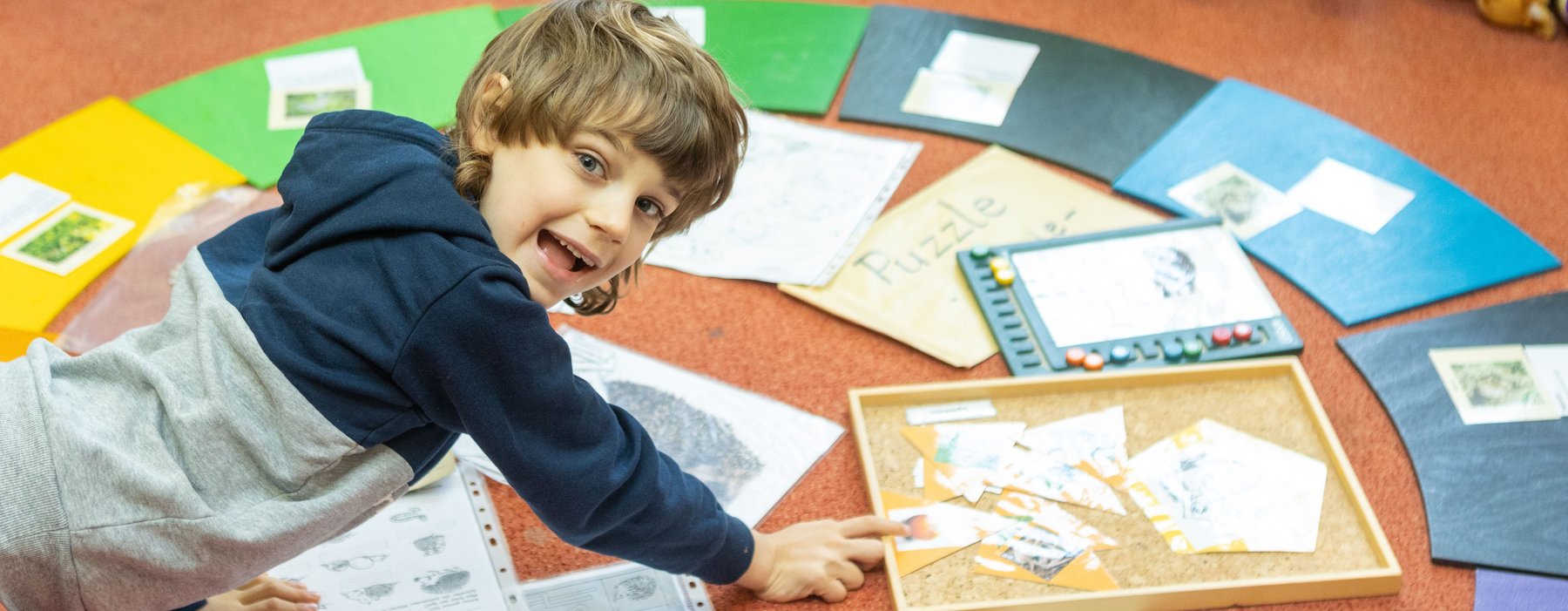 Ein kleiner Junge Freut sich über auf dem Boden liegenden Bildern
